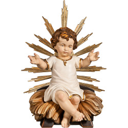 Niño Jesús vestido sentado en cuna con aureola