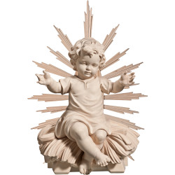Niño Jesús vestido sentado en cuna con aureola